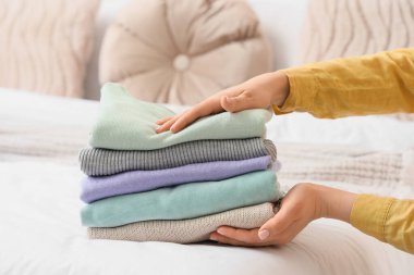 Kadın temiz giysileri yatağa koyuyor, yakın plan.