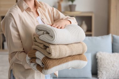 Kadın evinde kalın giysiler tutuyor.