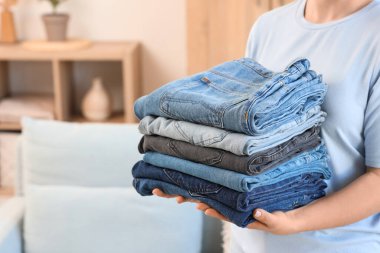 Kadının elinde bir yığın temiz kot var.