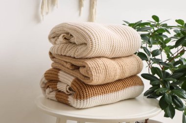 Masada kalın giysiler ve ışık duvarının yanında bitkiler var.