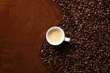 Kahve tozu, kavrulmuş fasulye ve bir fincan sıcak içecek karışımı.