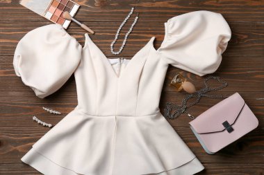 Ahşap arka planda şık elbise, aksesuarlar ve kozmetik ürünleri olan kompozisyon