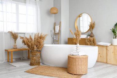 Küveti, aynası ve otları olan şık bir banyo.