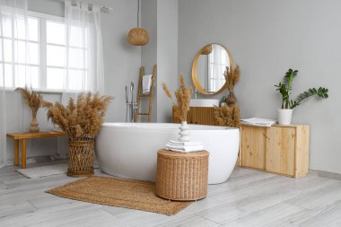 Küveti, aynası ve otları olan şık bir banyo.