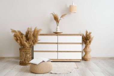 Şık bir odada beyaz duvarın yanında otlu çekmeceler.