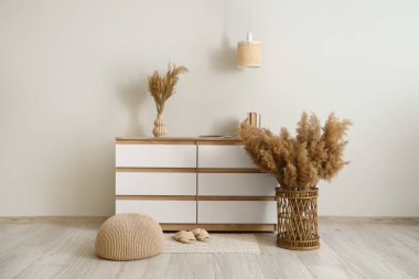 Şık bir odada beyaz duvarın yanında otlu çekmeceler.