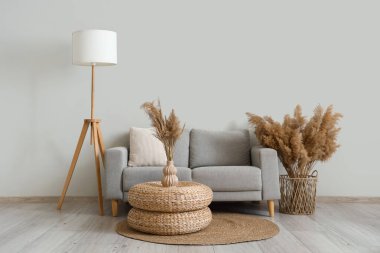 Gri kanepeli, hasır puflu ve otlu şık bir oturma odası.