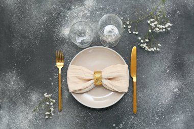 Altın çatal bıçak takımı ve karanlık arka planda çingene çiçekleri olan güzel bir masa.