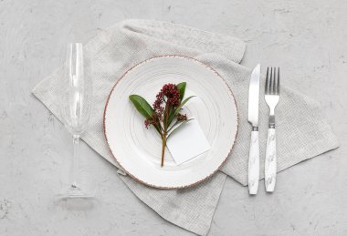 Boş kart ve gri arka planda skimmia japonica bitkisi olan güzel masa ayarları