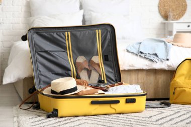 Otel odasında giysiler ve seyahat aksesuarlarıyla dolu bavulları boşalttım.