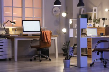 Geceleri masaları ve parlayan lambaları olan ofis içi.