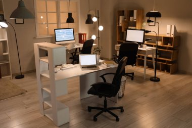 Masaları ve parlak lambaları olan programcı ofisinin içi