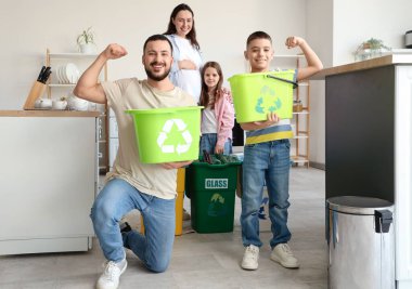 Mutfakta kaslarını gösteren konteynırları olan bir aile. Küresel Geri Dönüşüm Günü