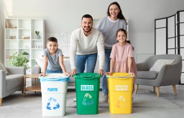 Evde çöp konteynırları olan bir aile. Küresel Geri Dönüşüm Günü