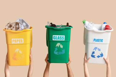 Bej arka planda çöp konteynırları olan bir sürü el. Küresel Geri Dönüşüm Günü