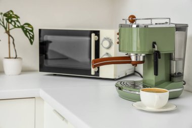 Mutfak tezgahında bir fincan espresso ile kahve makinesi, yakın plan.