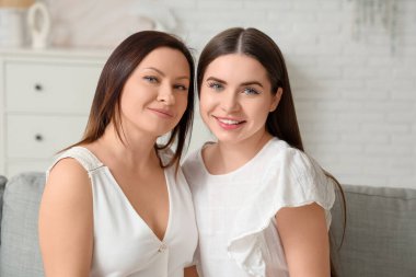 Güzel, olgun bir kadın ve küçük kızı oturma odasında kanepede oturuyor. Anneler Günü kutlaması