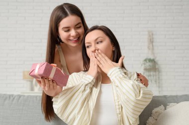 Oturma odasında hediye kutusu olan olgun bir kadın ve genç kızı. Anneler Günü kutlaması