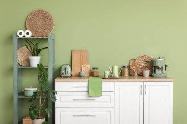 Mutfağın içinde çaydanlık, bir kavanoz kuru çay ve fincanla yeşil duvarın yanında.