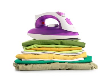 Beyaz arka planda izole edilmiş temiz giysi yığınına sahip modern demir.
