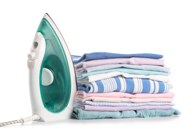 Beyaz arka planda izole edilmiş temiz giysi yığınına sahip modern demir.