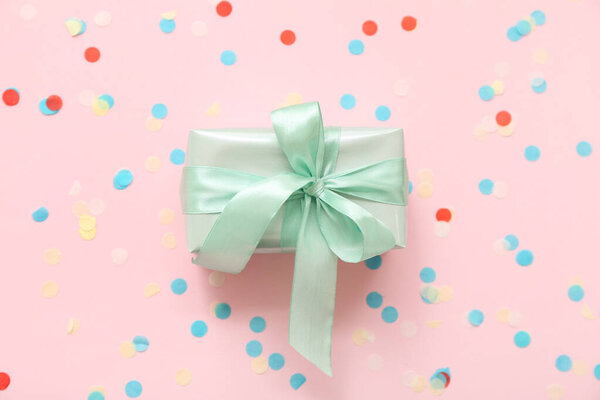 Зеленая подарочная коробка и конфетти на розовом фоне