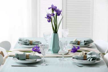 Anneler Günü kutlaması için güzel bir masa ve yemek odasında süsen çiçekleri olan vazo.