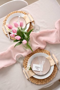 Anneler Günü kutlaması için güzel bir masa ve yemek odasında lale çiçekleri olan vazo.