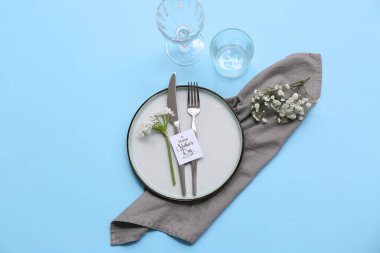 Tebrik kartı ve mavi arka planda güzel çiçekler olan şık bir masa. Anneler Günü kutlaması