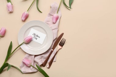 Tebrik kartı ve bej arka planda lale çiçekleri olan güzel bir masa. Anneler Günü kutlaması