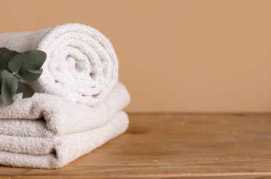 Temiz havlular ve okaliptüs dalı ahşap masa üzerinde renk arkaplanına karşı