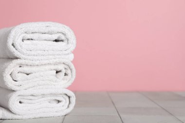 Pembe duvara karşı gri döşeme üzerinde temiz havlular yığını