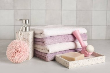 Açık fayans duvarına karşı masasında temiz havlular olan banyo malzemeleri.
