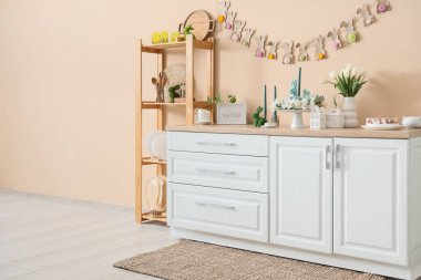 İçinde çiçekler ve bej duvarın yanındaki tezgahta Paskalya süsleri olan festival mutfağı.