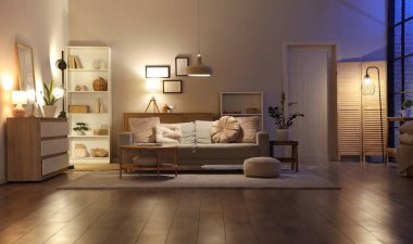 Oturma odasının içinde kanepe, raf ünitesi ve akşam lambaları var.