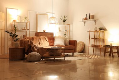 Oturma odasının içinde kahverengi kanepe, raf üniteleri ve akşam lambaları var.