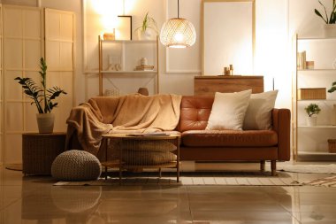 Oturma odasının içinde kahverengi kanepe, raf üniteleri ve akşam lambaları var.