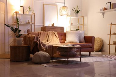 Oturma odasının içinde kahverengi kanepe, raf üniteleri ve akşam lambaları var.