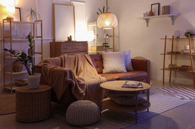 Oturma odasının içinde kahverengi kanepe, raf üniteleri ve akşam lambaları var.