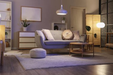 Gri kanepeli, masalı ve parlayan lambalı oturma odasının içinde.