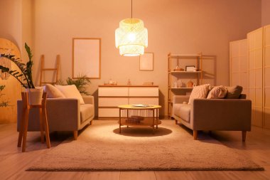 Geceleri kanepeleri, masası ve parlayan lambası olan oturma odasının içinde.