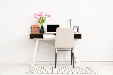 Çalar saati, dizüstü bilgisayarı ve vazoda güzel lale çiçekleri olan modern işyeri.