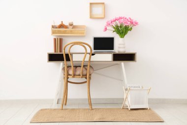 Rafları, kitapları, dizüstü bilgisayarı ve vazoda güzel lale çiçekleri olan modern işyerinin içini.