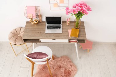 Tabureleri, güzel lale çiçekleri, dizüstü bilgisayarı ve kırtasiyesi olan modern işyeri.