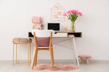 Tabureleri, güzel lale çiçekleri, dizüstü bilgisayarı ve kırtasiyesi olan modern işyeri.