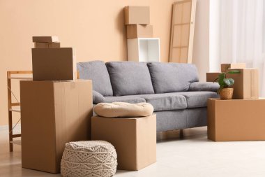 Oturma odasının içinde gri kanepe ve bej duvarın yanında bir sürü paket var.