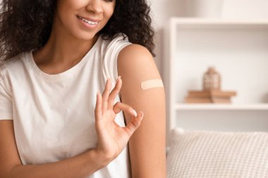 Tıbbi bandı olan genç bir Afro-Amerikalı kadın aşıdan sonra iyi görünüyor.