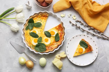 Cut Easter egg tart with pussy willow branches and tulip flowers on grey background