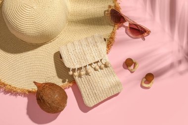Pembe arka planda şık plaj aksesuarları ve hindistan cevizi olan kompozisyon