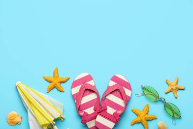 Renkli arka planda mini şemsiyeli kompozisyon, parmak arası terlik, güneş gözlüğü ve deniz kabuğu